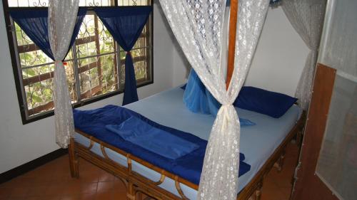 a bedroom with a bed and two windows with curtains at Mut Mee Garden Guest House in Nong Khai