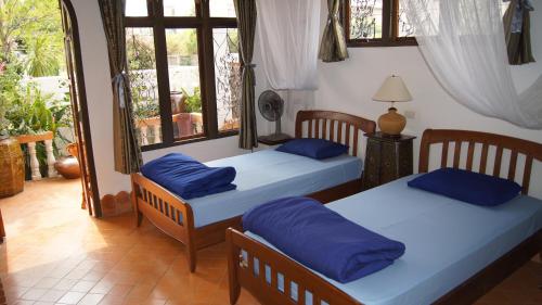 two beds in a room with blue pillows at Mut Mee Garden Guest House in Nong Khai