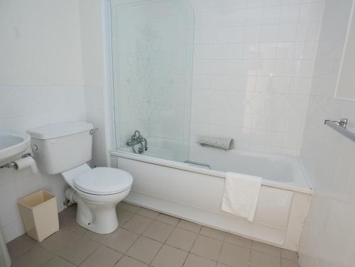 a white bathroom with a toilet and a bath tub at Spanish Cove Holiday Homes Sleeps 5 by Trident Holiday Homes in Kilkee