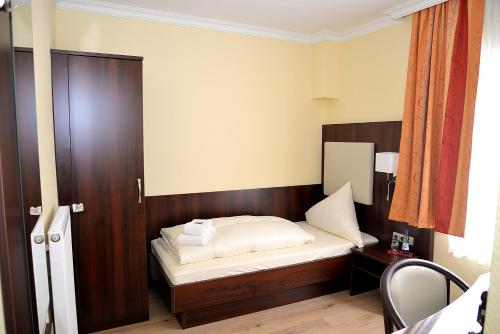 a small bedroom with a bed with a wooden headboard at Hotel Neugrabener Hof in Hamburg