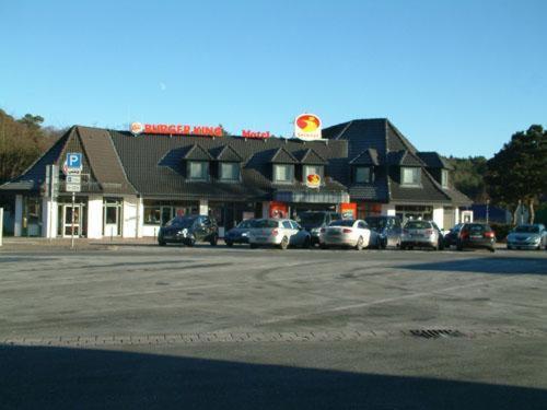 un edificio con coches estacionados en un estacionamiento en Raststätte Hollenstedt, en Hollenstedt