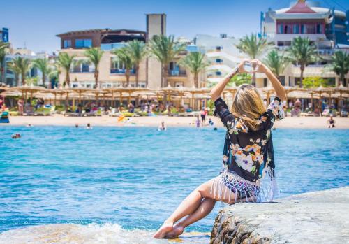 a young girl sitting on a wall near the water at Seagull Beach Resort - Families and Couples Only in Hurghada
