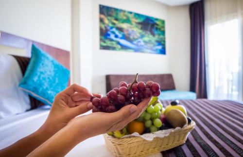 a person holding a basket of fruit on a bed at Seagull Beach Resort - Families and Couples Only in Hurghada