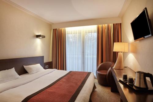 a hotel room with a bed and a television at Hôtel Spa Du Béryl in Bagnoles de l'Orne