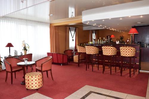 un restaurante con bar, mesas y sillas en Hotel Le Pole Europeen, en Aubange