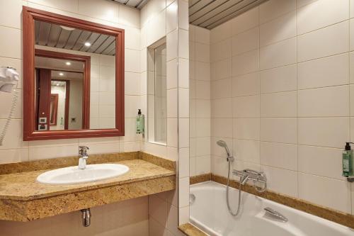 een badkamer met een wastafel, een bad en een spiegel bij Hôtel Spa Du Béryl in Bagnoles de l'Orne