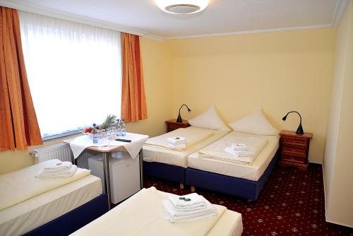ein Hotelzimmer mit 3 Betten und einem Fenster in der Unterkunft Hotel Neugrabener Hof in Hamburg