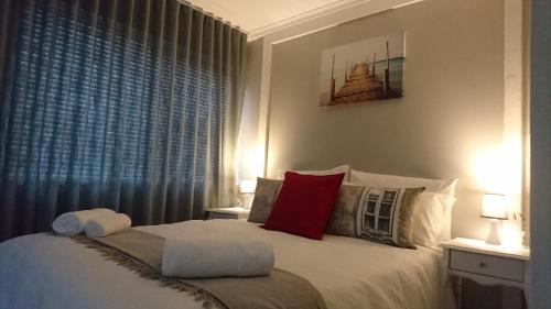 a bedroom with a bed with red pillows and a window at Hamilton Garden Suites in Parklands