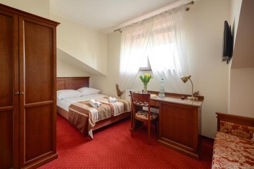 a bedroom with a bed and a desk and a window at Dworek Vesaria in Lublin