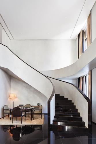a spiral staircase with a dining room and a table at Armani Hotel Milano in Milan