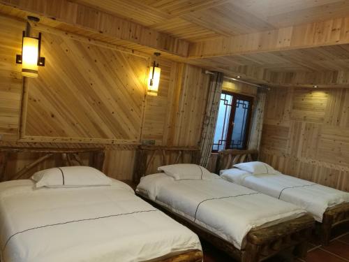 two beds in a room with wooden walls at Longji Holiday Hotel in Longsheng