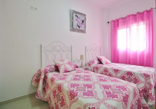 ネルハにあるCasa San Juan SpainSunRentals 1088のベッドルーム1室(ベッド2台、ピンクのカーテン付)