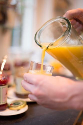 a person is pouring orange juice into a glass at Villa Magnolia in Oostkapelle