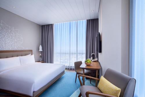 a hotel room with a large white bed and a desk at Mercure Jakarta Pantai Indah Kapuk in Jakarta