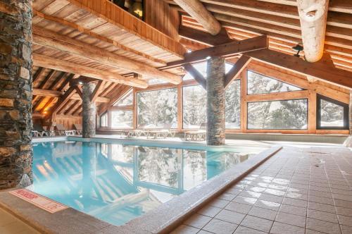 - une piscine intérieure dans un bâtiment doté de plafonds en bois dans l'établissement Residence Les Fermes de Meribel - maeva Home, à Méribel