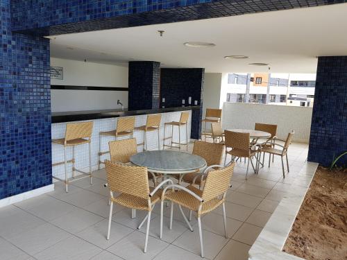 un patio con tavoli, sedie e un bar di Apartamento na praia de Armação a Salvador