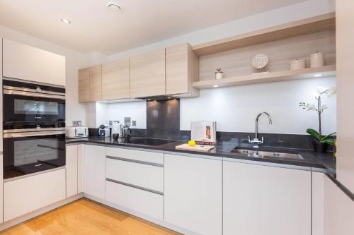 a kitchen with white cabinets and black counter tops at Portobello Apt with Floor-to-Ceiling Views in London