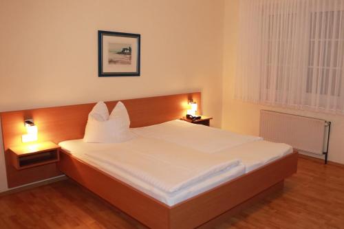 ein Schlafzimmer mit einem großen weißen Bett mit zwei Lampen in der Unterkunft Hotel Ratsstuben in Rehden