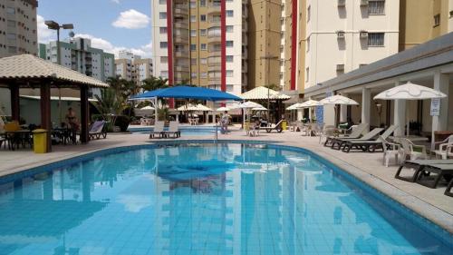 une grande piscine bleue avec des tables et des parasols dans l'établissement Privé das Thermas Caldas Novas, à Caldas Novas