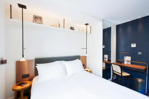 a bedroom with a white bed and a desk at H&ocirc;tel Amastan Paris in Paris