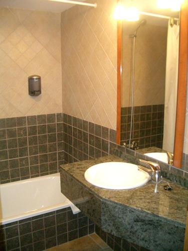 a bathroom with a sink and a mirror and a tub at Hotel Sant Roc in Camprodon