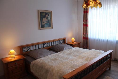 een slaapkamer met een groot bed en 2 lampen op tafels bij Ferienwohnung-LOGA in Leer