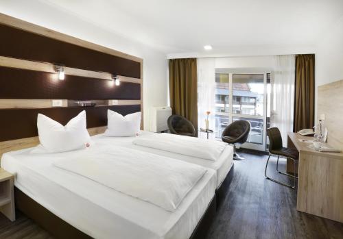 ランツフートにあるACHAT Hotel Kaiserhof Landshutの白い大型ベッド1台、デスクが備わる客室です。