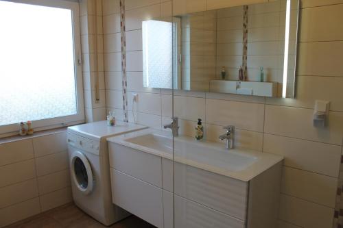 een badkamer met een wasmachine en een wastafel bij Ferienwohnung-LOGA in Leer