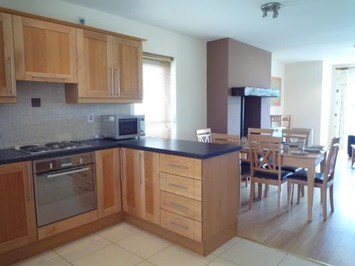 a kitchen with wooden cabinets and a dining room at Tralee Holiday Homes in Tralee