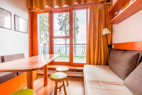 - un salon avec une table, un canapé et une fenêtre dans l'établissement Résidences quartier Charmettoger - maeva Home, à Arc 1800
