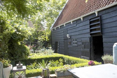 - un bâtiment noir avec un jardin en face dans l'établissement Lekker bij MaAs, à Dreischor