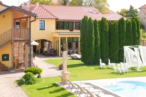 ein Haus mit einem Garten mit Stühlen und einem Pool in der Unterkunft Hotel Garni Klaret in Valtice