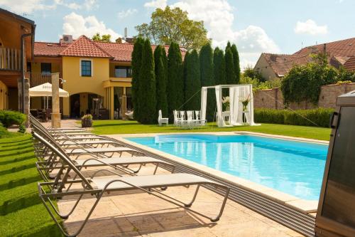 a swimming pool with lounge chairs in a yard at Hotel Garni Klaret in Valtice