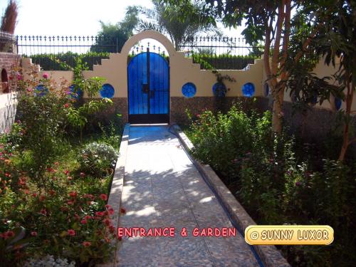 uma casa com uma porta azul num jardim em Sunny Luxor em Luxor