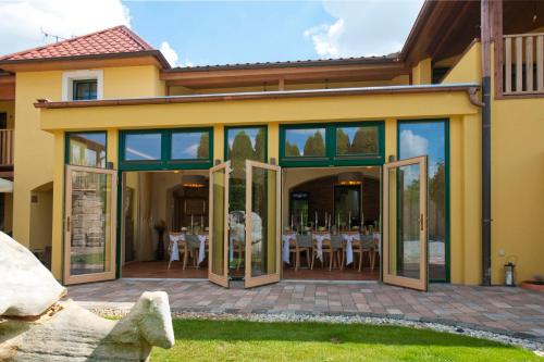 a house with glass doors and tables and chairs at Hotel Garni Klaret in Valtice