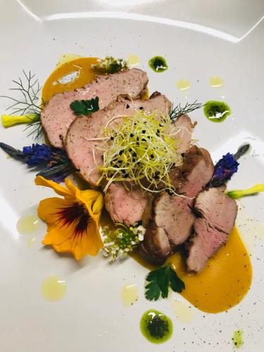 a plate of food with meat and flowers on it at Villa Greta Hotel Rooms & Suites in Taormina