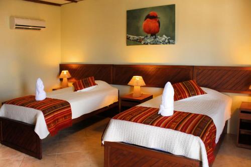 a hotel room with two beds and a red bird on the wall at Arena Blanca Eco Hotel in Puerto Baquerizo Moreno
