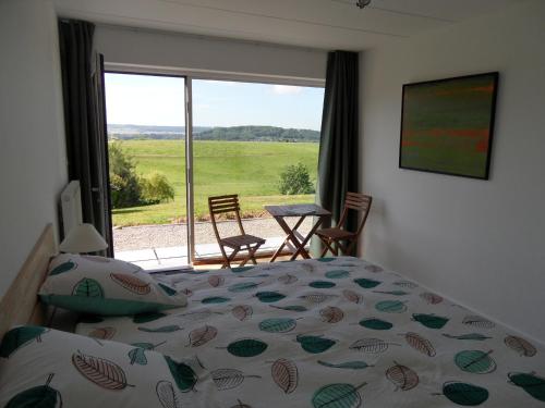 Schlafzimmer mit einem Bett und einem Fenster mit Aussicht in der Unterkunft Les chambres du Houmier in Rouvreux