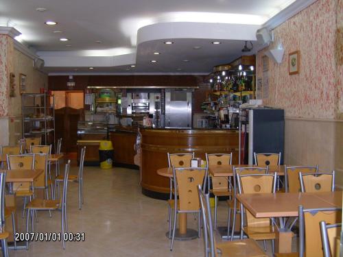 un restaurante con mesas y sillas y una cocina en Olhos Pretos, en Caldas da Rainha
