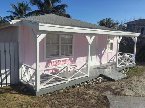 a pink house with a bench on the porch at Bimini Seaside Villas - Pink Cottage with Beach View in Alice Town
