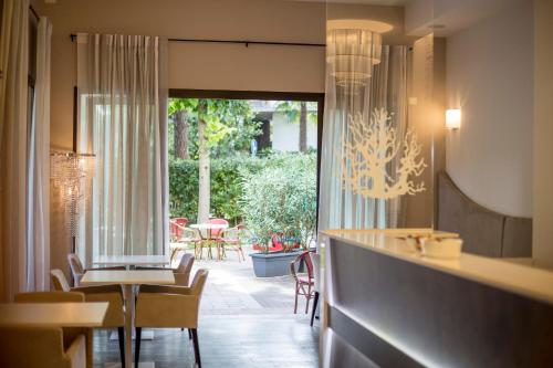 una sala da pranzo con tavolo, sedie e una finestra di Hotel Corallo a Milano Marittima