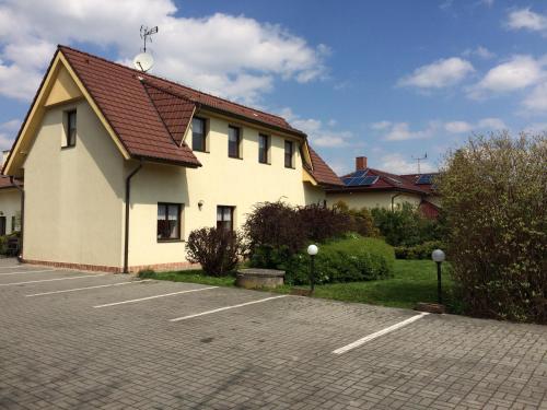 a white building with a red roof in a parking lot at Penzion Hůrka in Pardubice