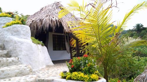 a small house with a thatch roof and some flowers at Quetzal Dorado Eco-Lodge by Mareygua in El Zaino