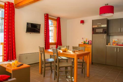 cocina con mesa de madera y sillas en una habitación en Goélia Les Chalets de Belledonne en Saint-Colomban-des-Villards