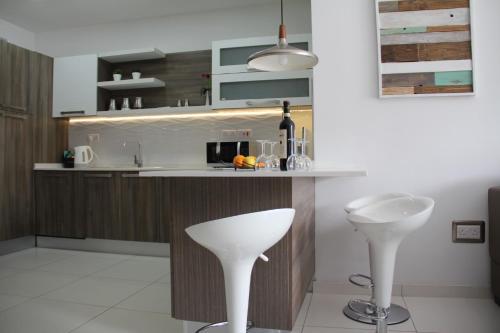 a kitchen with a counter and two white bar stools at Interlace Apartment with free parking in Marsaskala