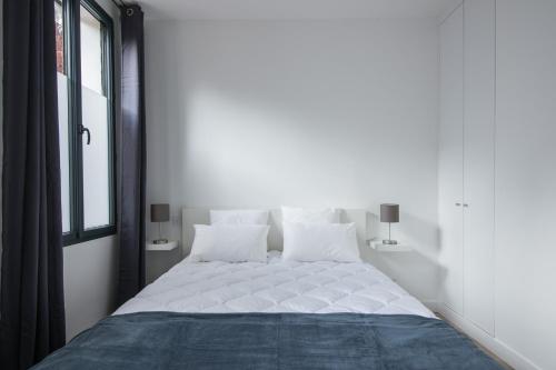 une chambre avec un lit avec des draps blancs et une fenêtre dans l'établissement L'Industriel, loft de 2 chambres, Villa Saint Charles, à Paris