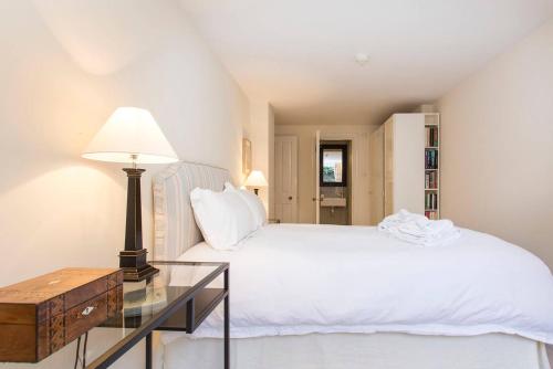 1 dormitorio con cama blanca y mesa de cristal en JOIVY Stylish 2 Bed, 2 bath flat with patio, near Victoria station, en Londres