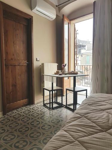 ein Schlafzimmer mit Bett, Tisch und Balkon in der Unterkunft Nonna Ninetta in Melfi