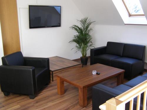 ein Wohnzimmer mit 2 Stühlen, einem Tisch und einem TV in der Unterkunft Hotel Alt Vinnhorst in Hannover