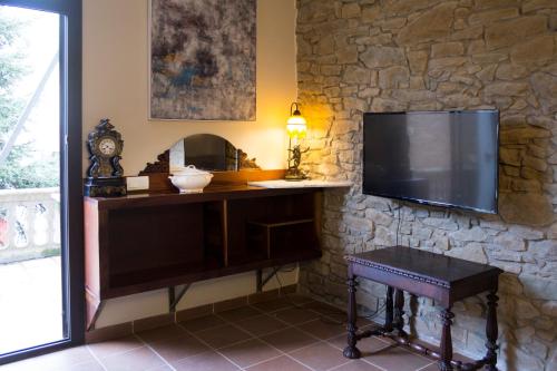 TV en una pared de piedra con mesa y taburete en Gallaret, en Sant Juliá de Vilatorta